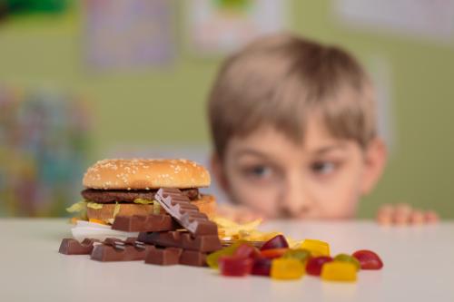 Un garçon regarde avec envie un hamburger et des sucreries