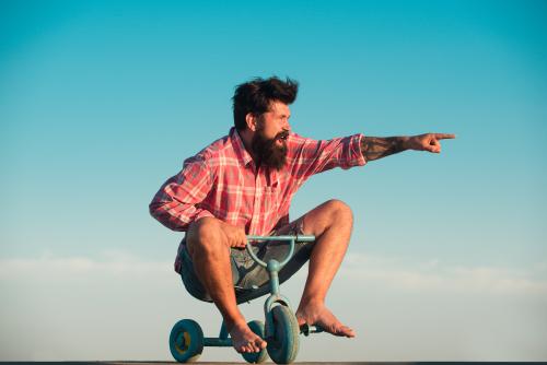 Bearded man on tricycle pointing ahead