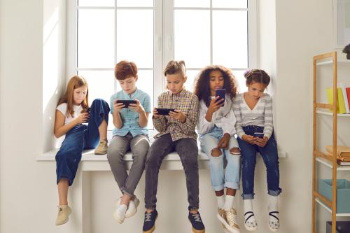 School children sitting together looking at their smartphones